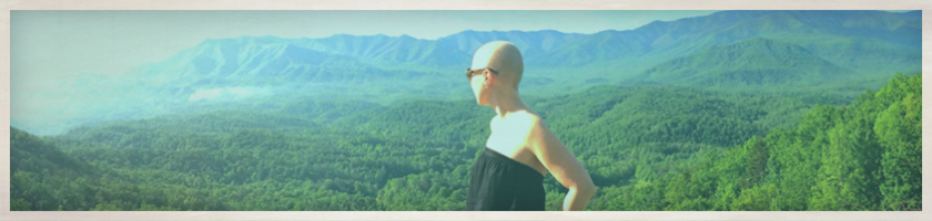 Woman in black dress looking out over a green valley