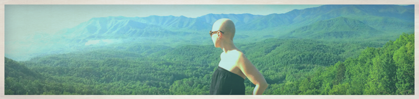 Woman in black dress looking out over a green valley